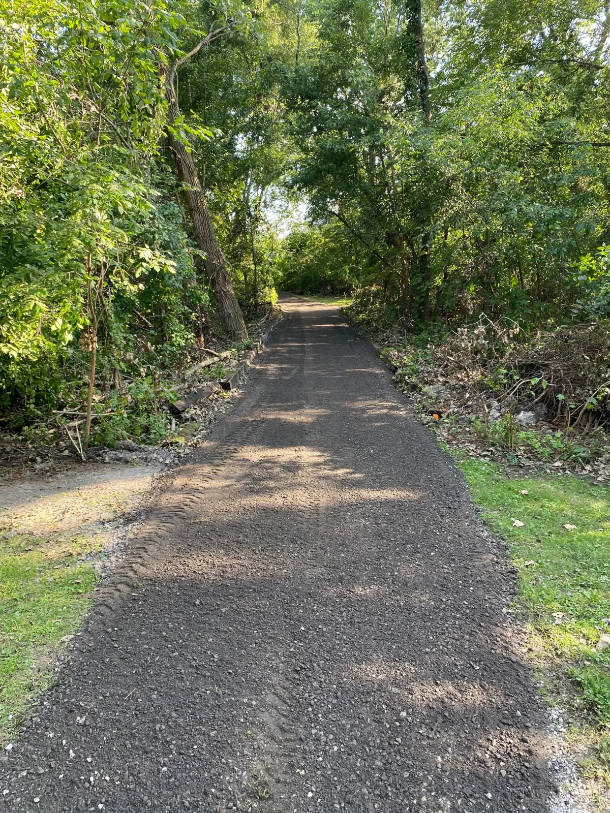 Graded driveway with fresh stone, clean edges, and railroad-tie border